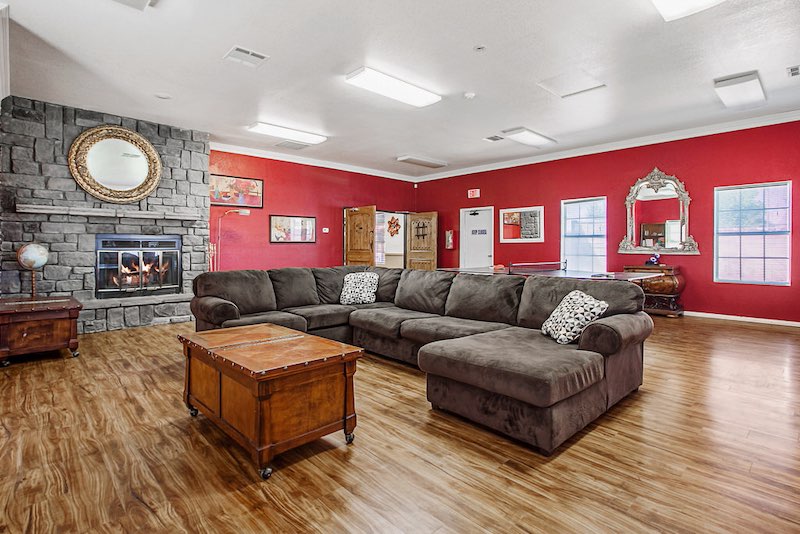 Indoor Recreation Area with Stone Fireplace, Couch, and Wood Flooring